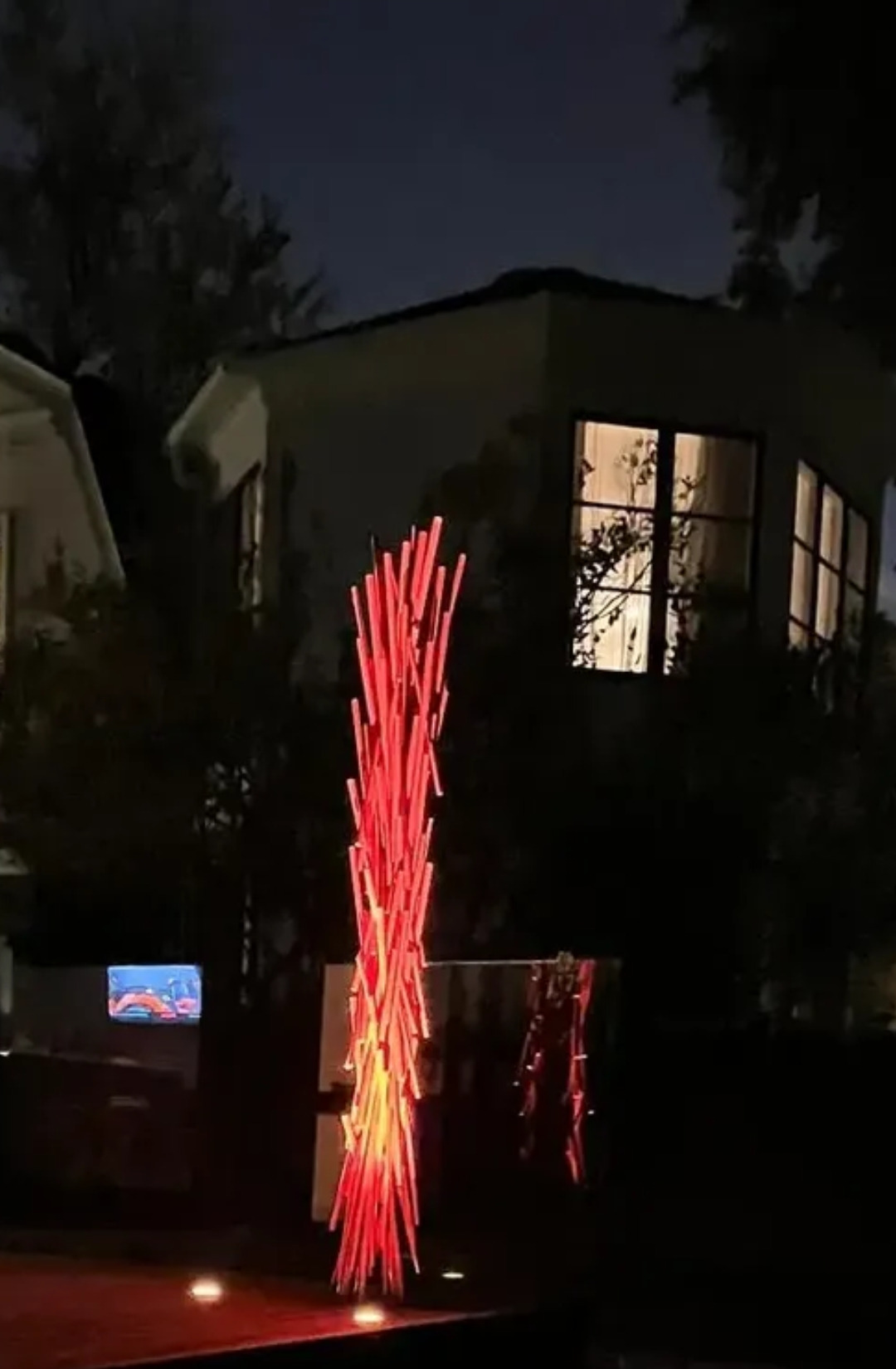 The same sculpture at night, uplit from two in-ground fixtures at its base
